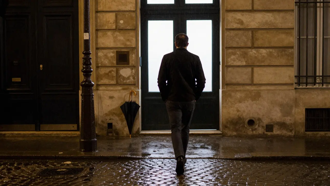 A man walking away alone from a Paris doorway at night, rain reflecting on the street.